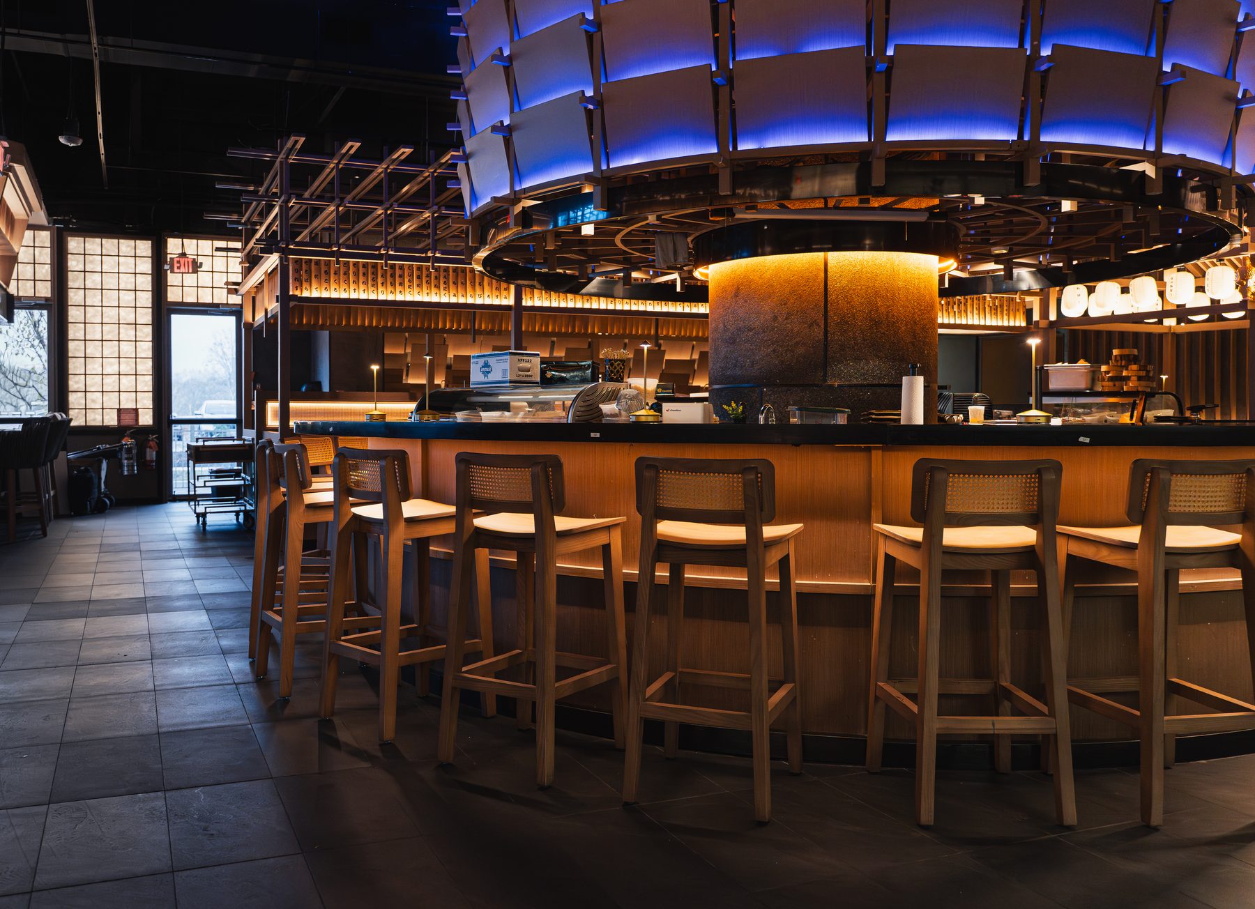 Gyusan's round sushi bar in Columbia, MD: a curved wood counter with cane stools under a blue-lit ring of panels