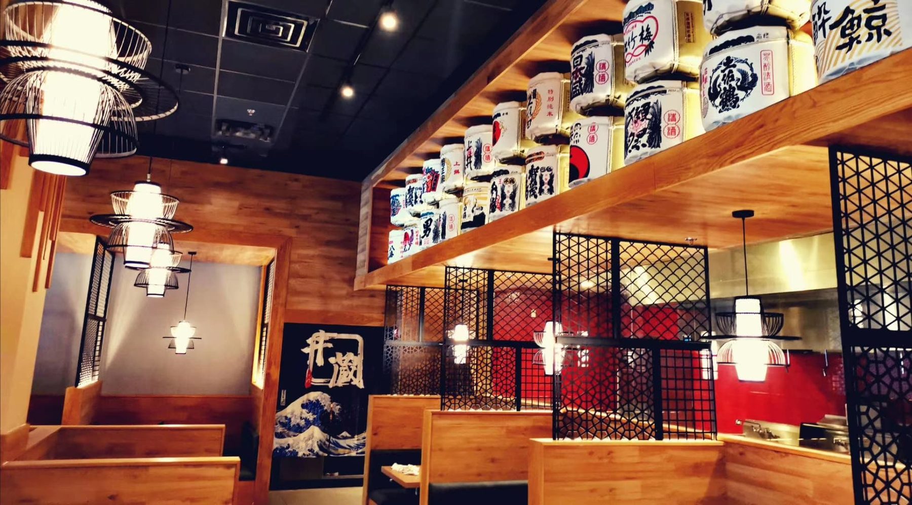 Gyuzo BBQ's dining room in Rockville, MD, with wood booths, a backlit shelf of white sake barrels and black lattice screens