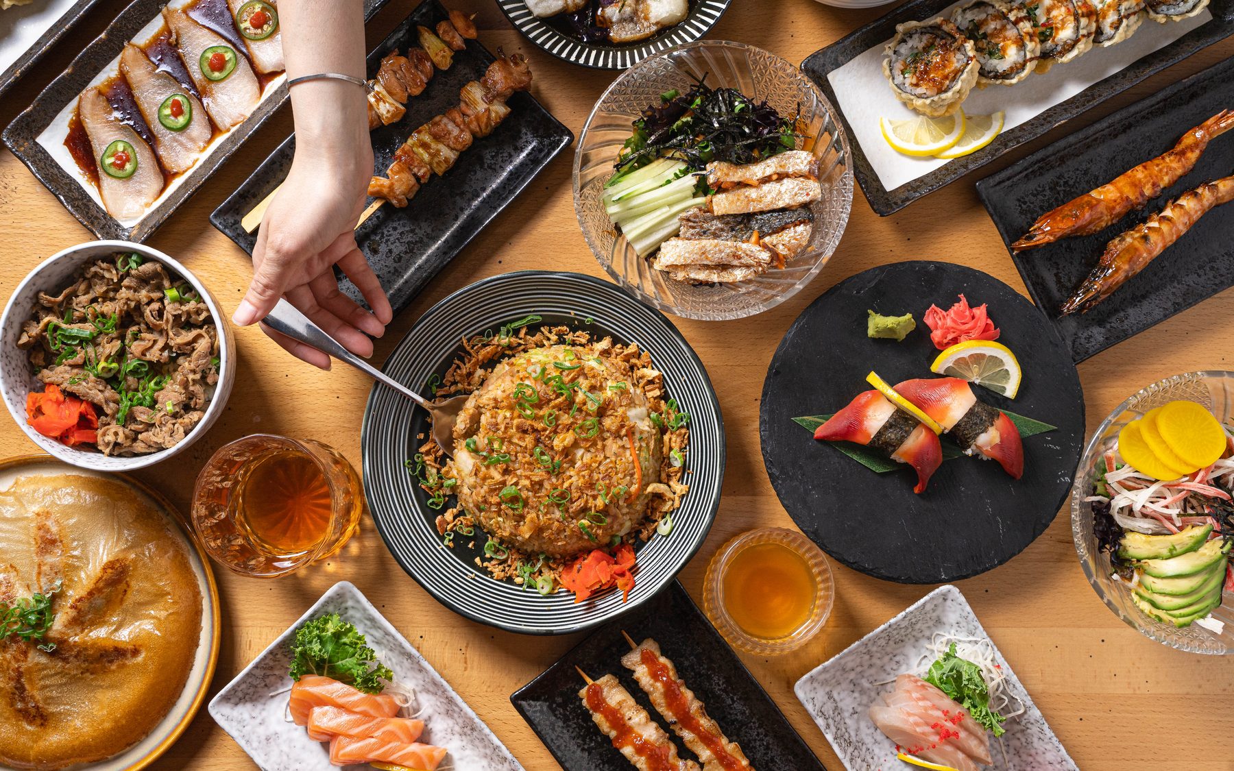Overhead izakaya spread at Izakaya 68 in Hunt Valley, MD: fried rice with crispy shallots, yakitori, sushi rolls, sashimi and drinks