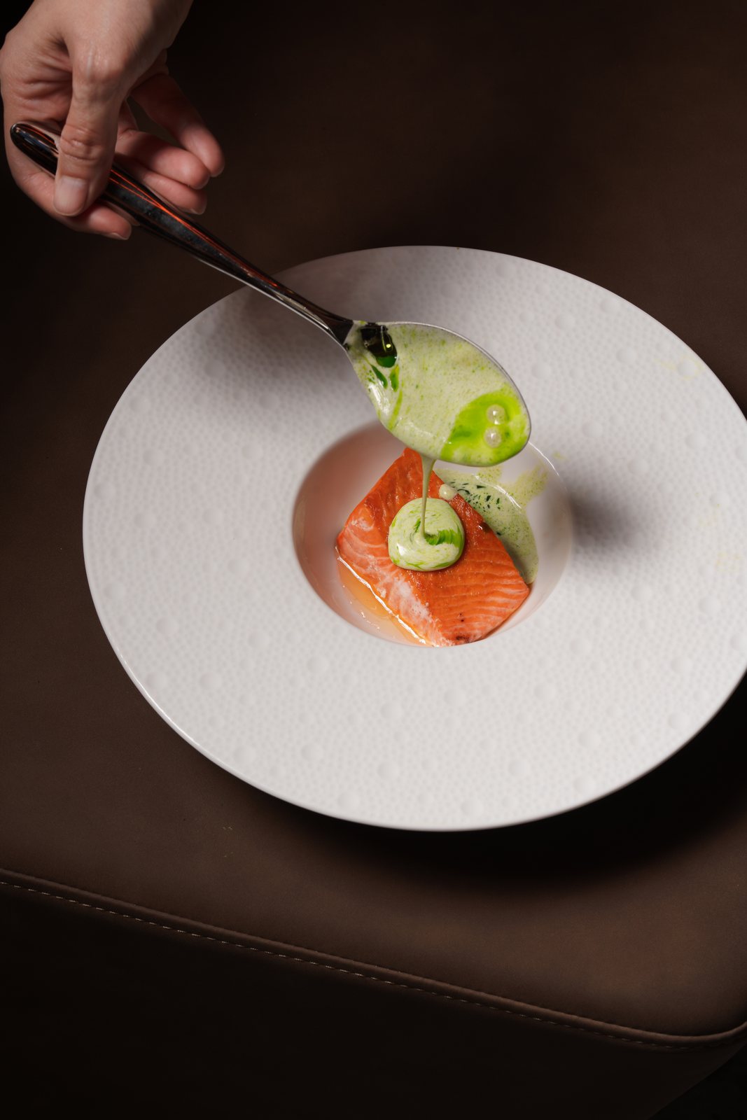 Fennel cream spooned over the Creamy Cedar Salmon at the table at MUI Supper Club